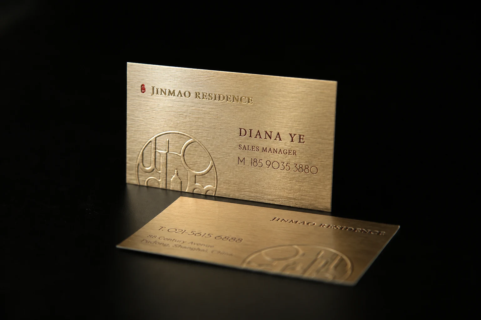 Metallic paper stock business cards with brushed gold surface and red foil deboss detail