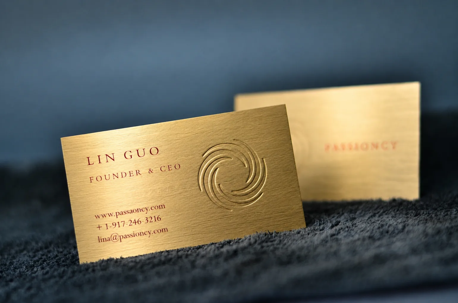 Brushed gold metallic paper business card with deep debossing and red printing
