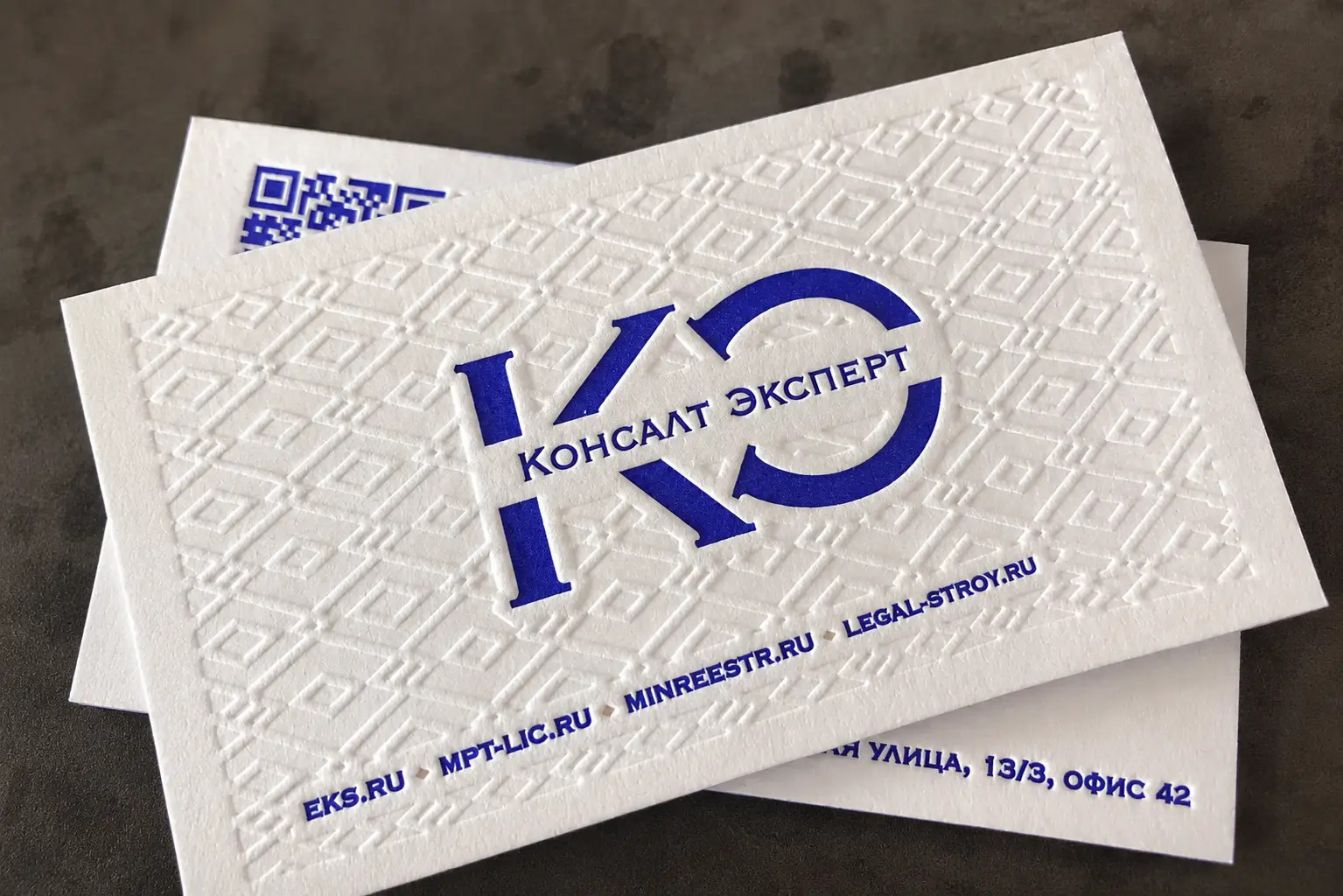 Cream cotton business card with a large blind deboss monogram and refined private design studio typography.