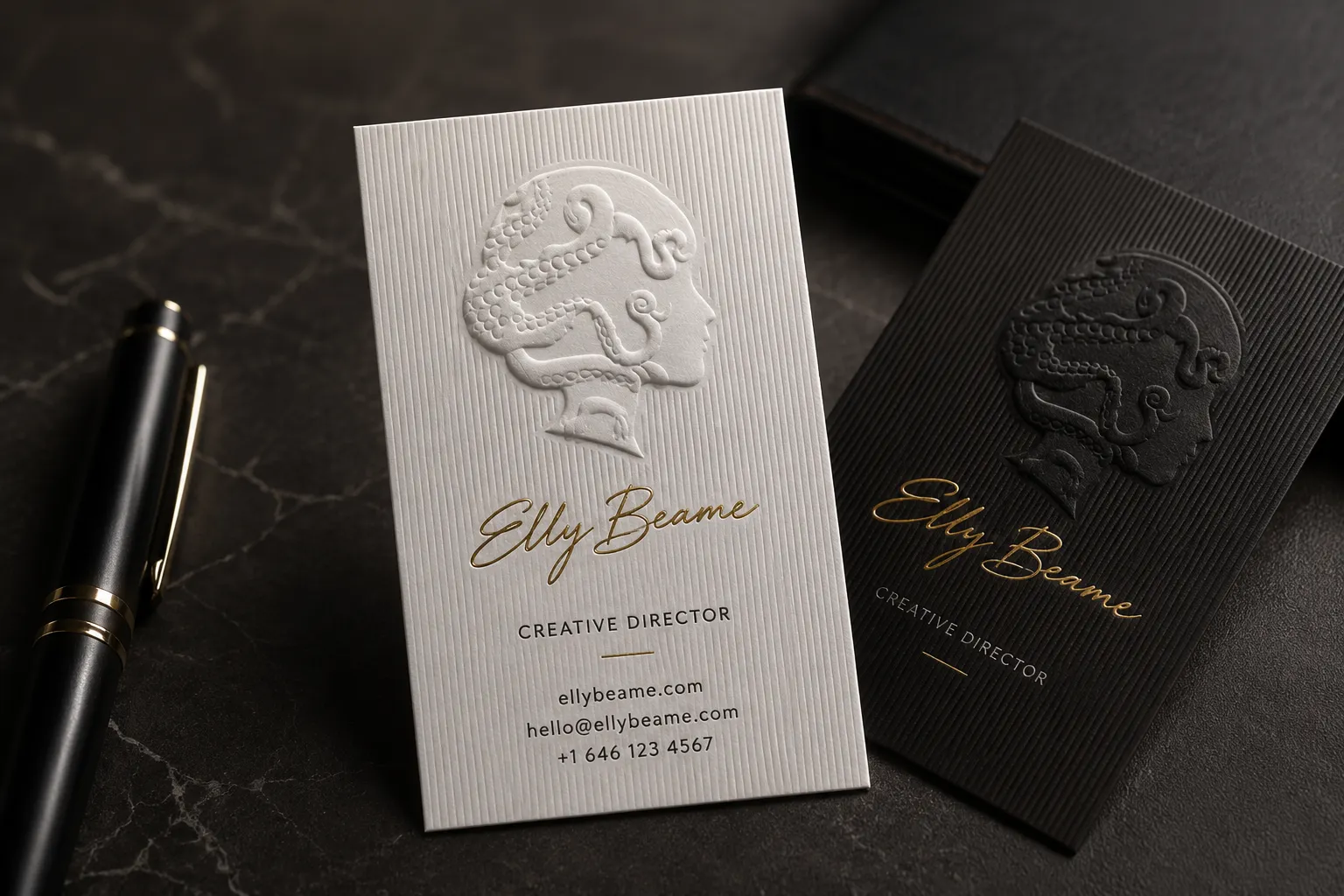 White and black business cards with a large sculpted embossed portrait logo and metallic brand text.
