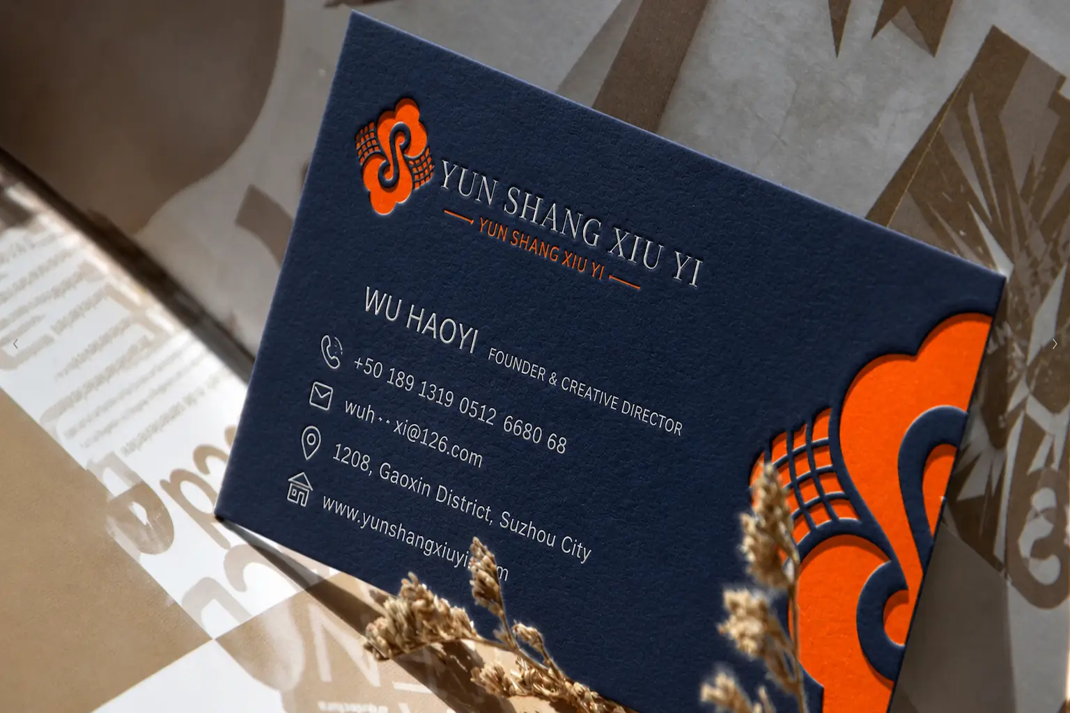 Triplex business card with a blue-orange-blue color core featuring intricate laser-cut patterns, high-opacity white ink printing, and pearlescent white hot foil stamping