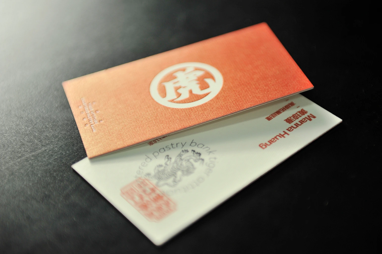 730gsm ivory textured paper business card with warm orange full coverage print and subtle embossed logo detail