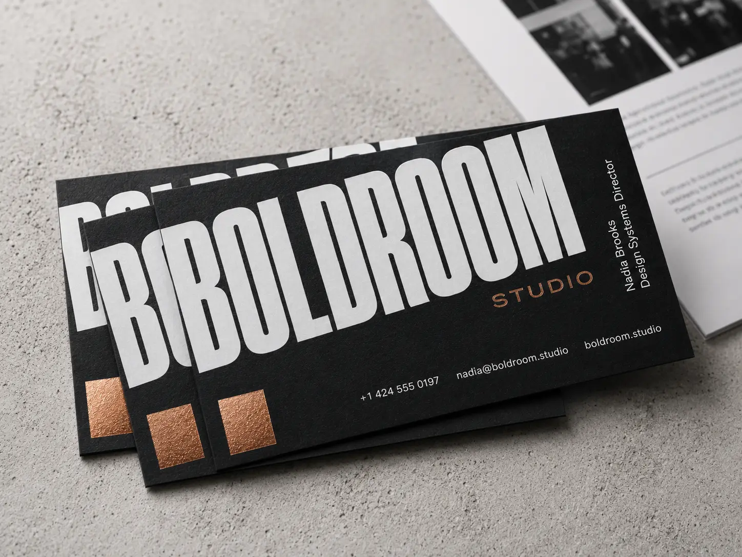 Black business card with bold white typography and warm metallic accent blocks for a creative studio layout.