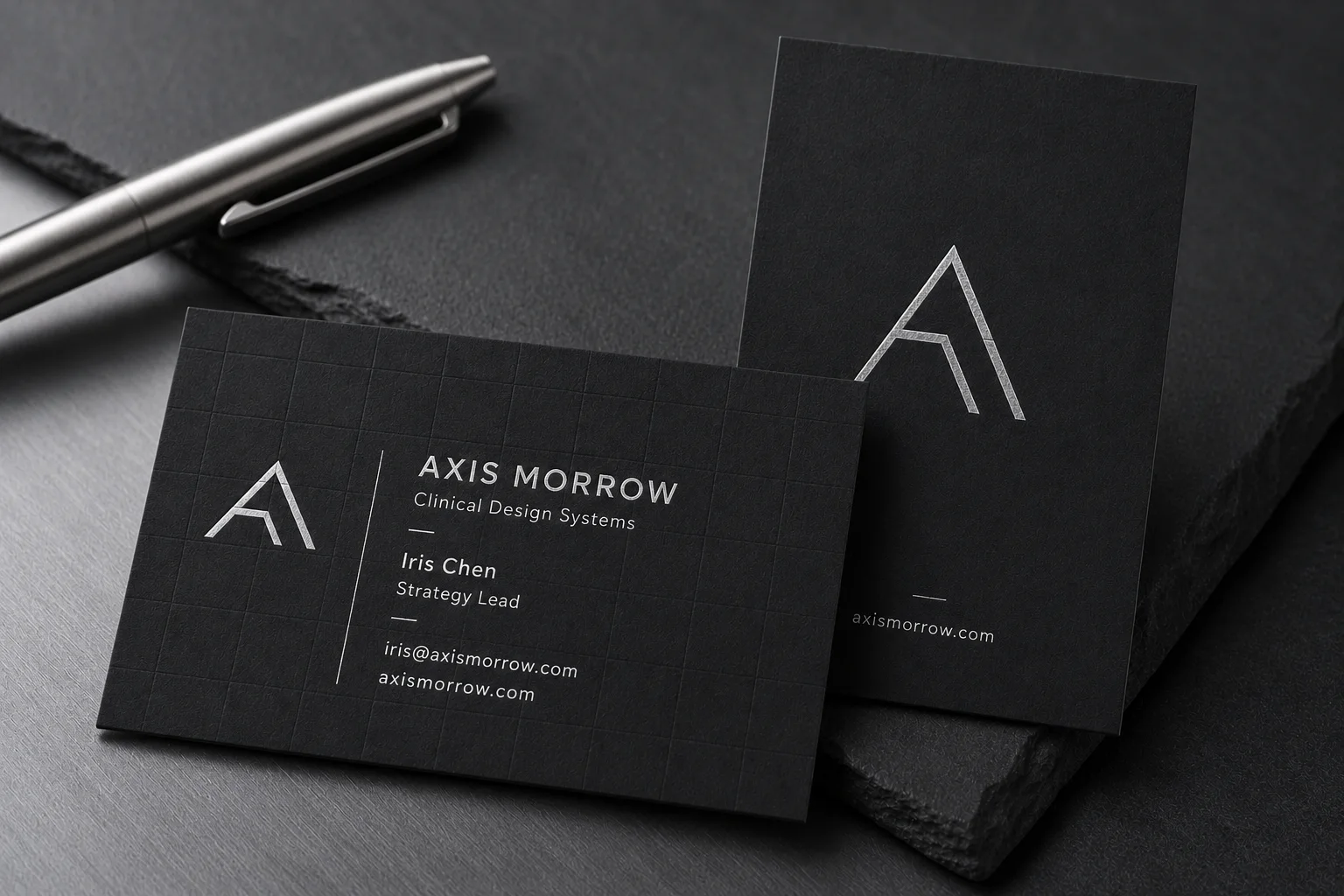 Black matte business cards with cool platinum silver foil stamping, white ink text and subtle blind deboss detail.