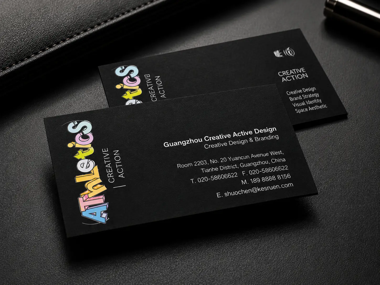 Black business card with colorful foil-style typography accents and clean contact information.