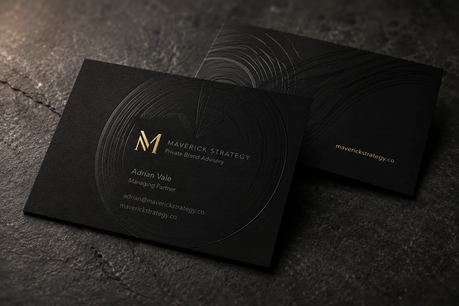 Matte black business card with black-on-black spot UV texture and a restrained gold foil monogram.