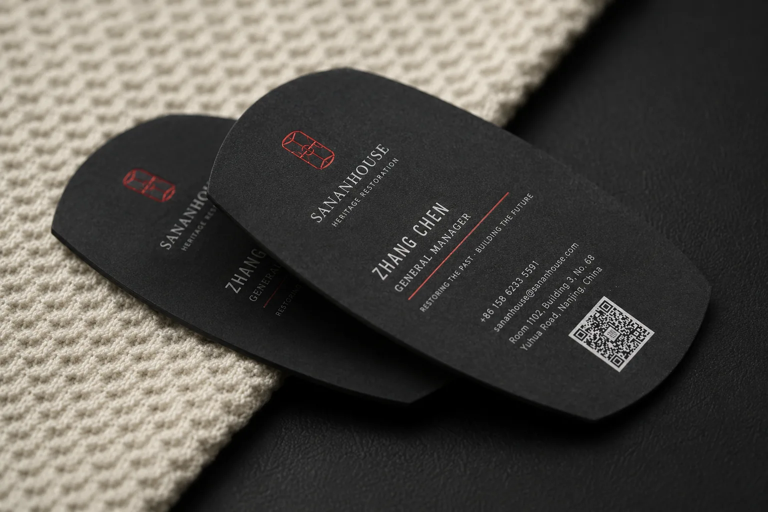 Rounded black business cards with white ink text, red accent details and a clean QR code layout.
