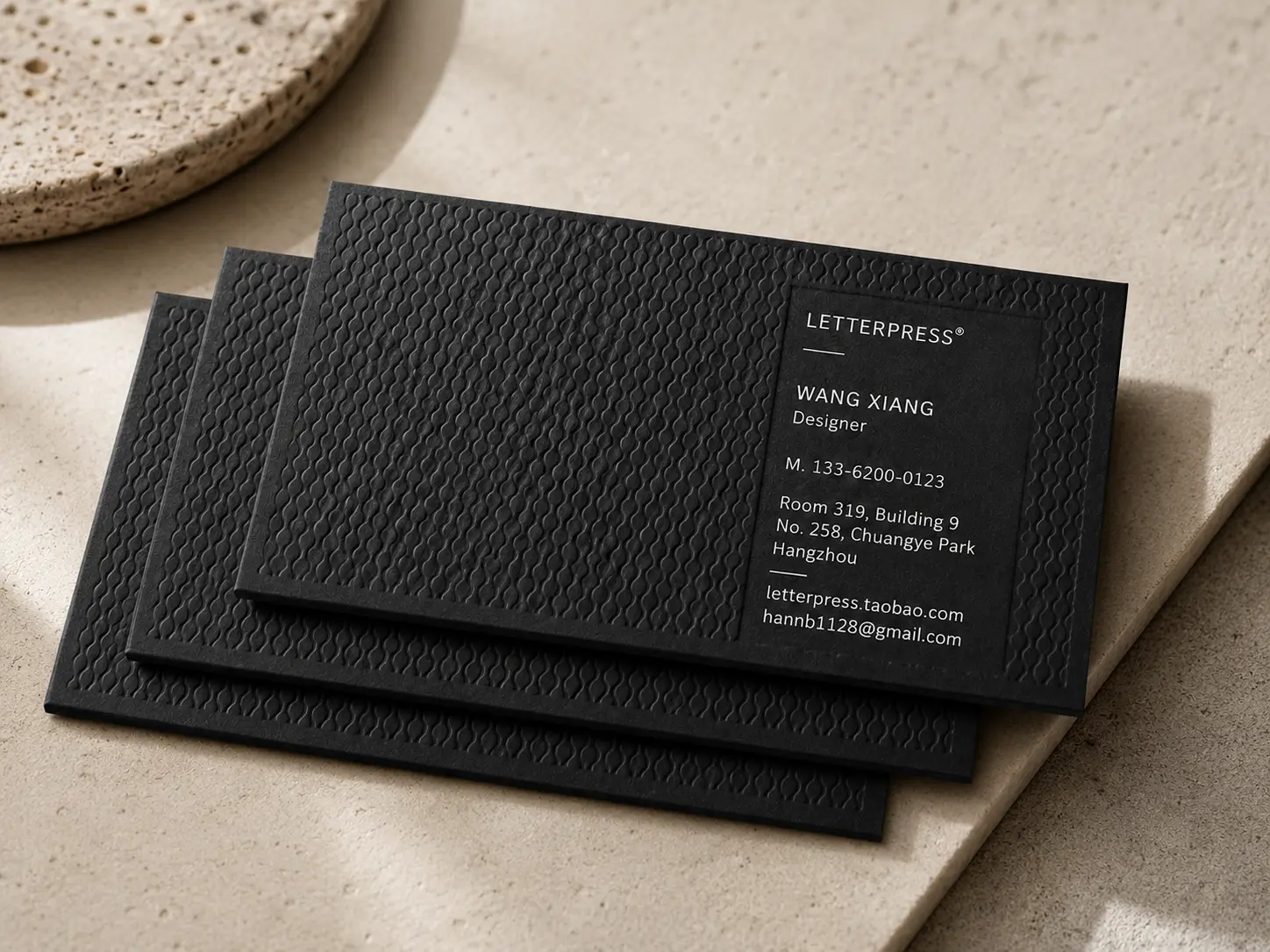 Stacked black business cards with visible textured paper surface and clean white ink information.