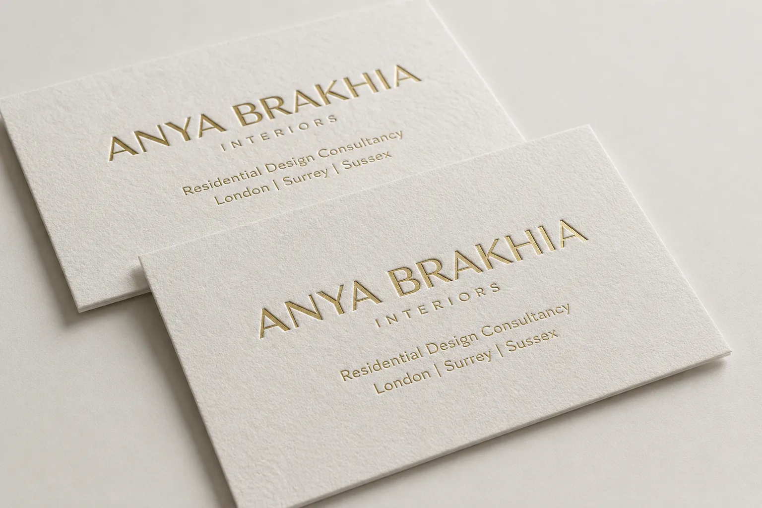 Light cotton-style business cards with gold foil typography and a soft premium paper surface.