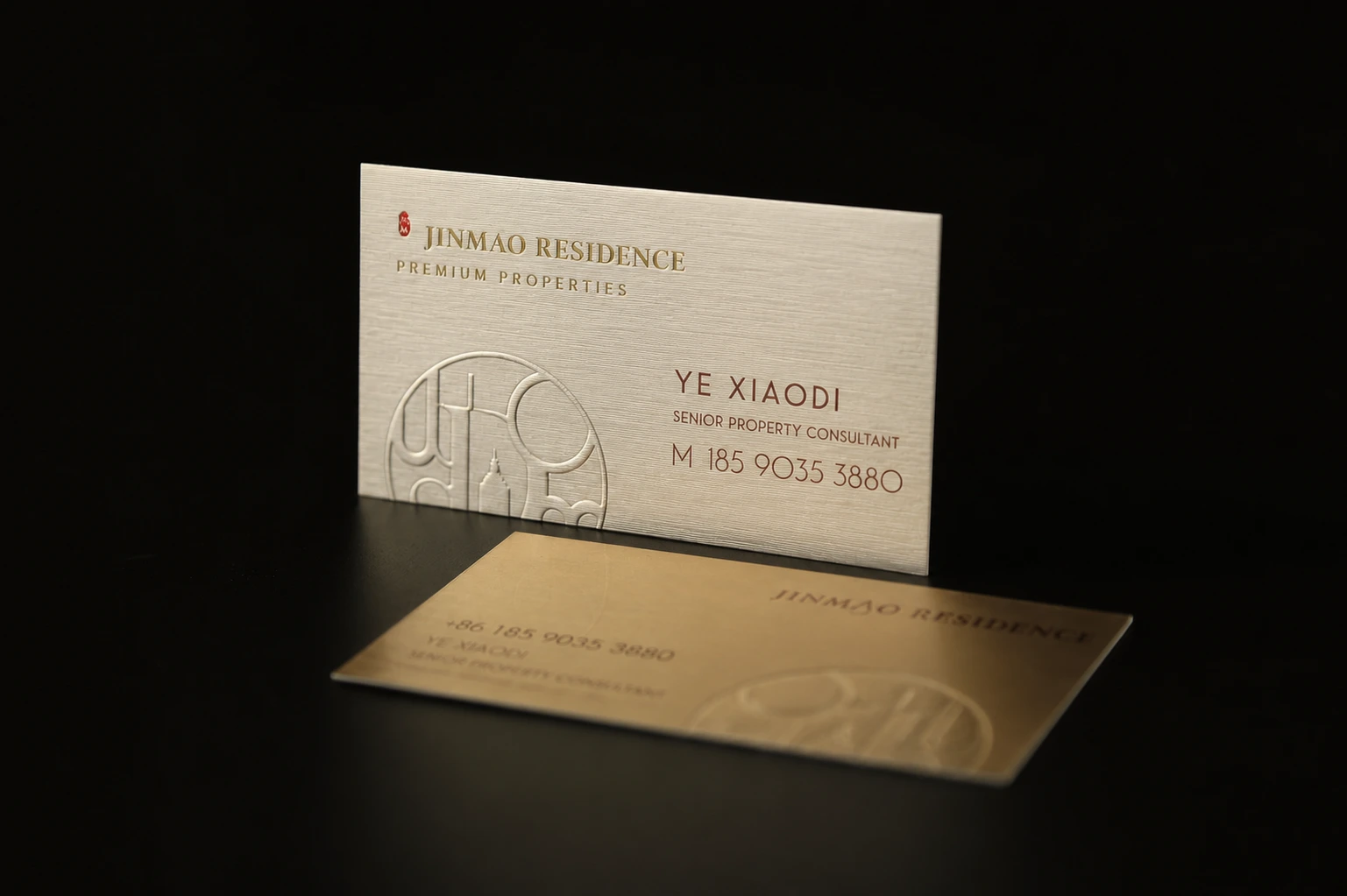 Luxury business card on a dark background with subtle debossed artwork and metallic foil detail.