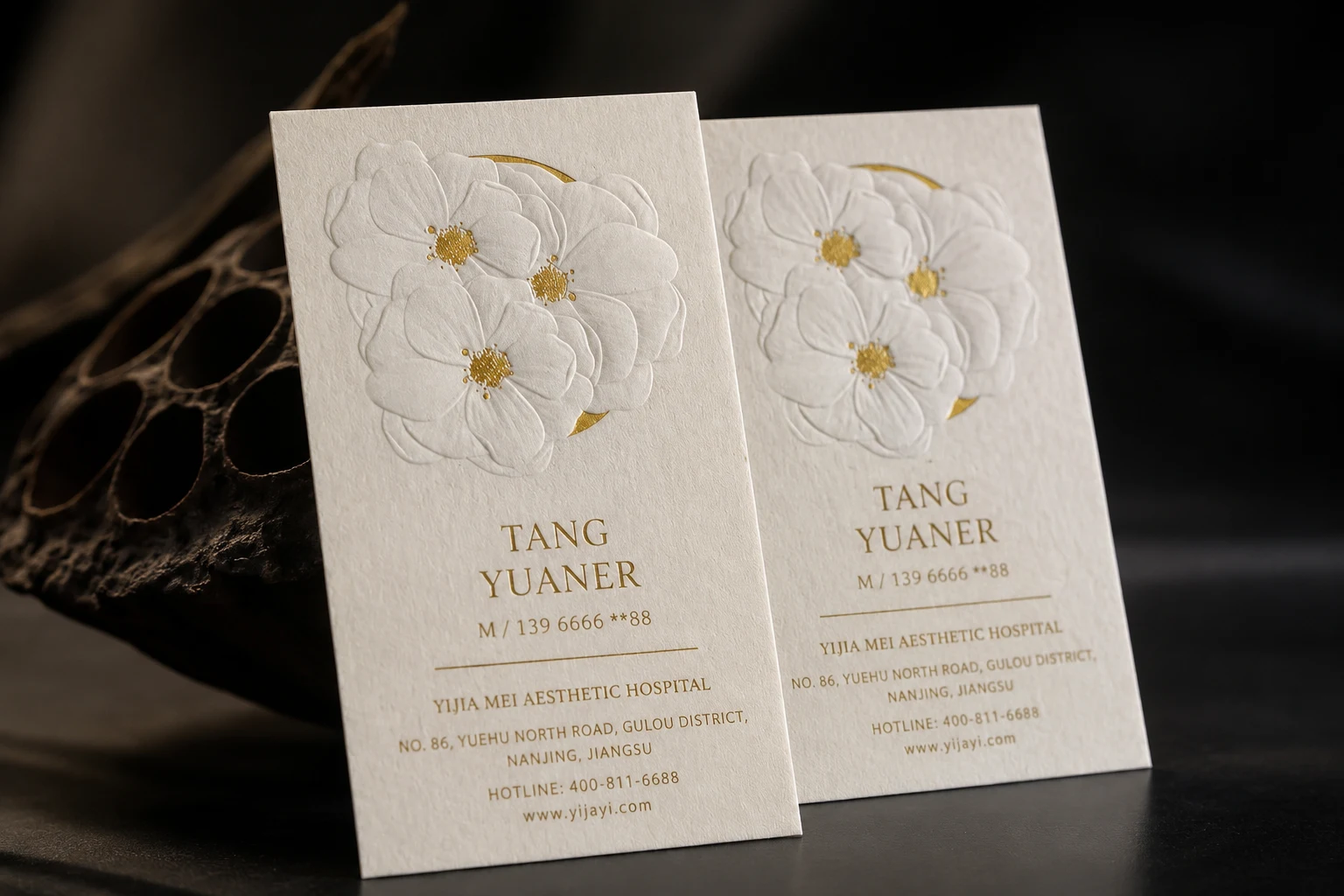 White cotton business cards with subtle blind embossed floral artwork and warm premium stationery styling.