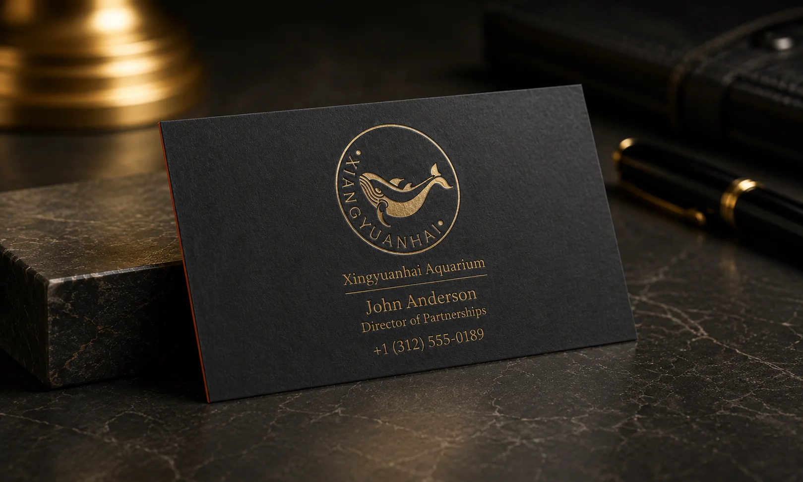 Black business card with gold foil logo detail and a tactile raised or pressed brand mark effect.