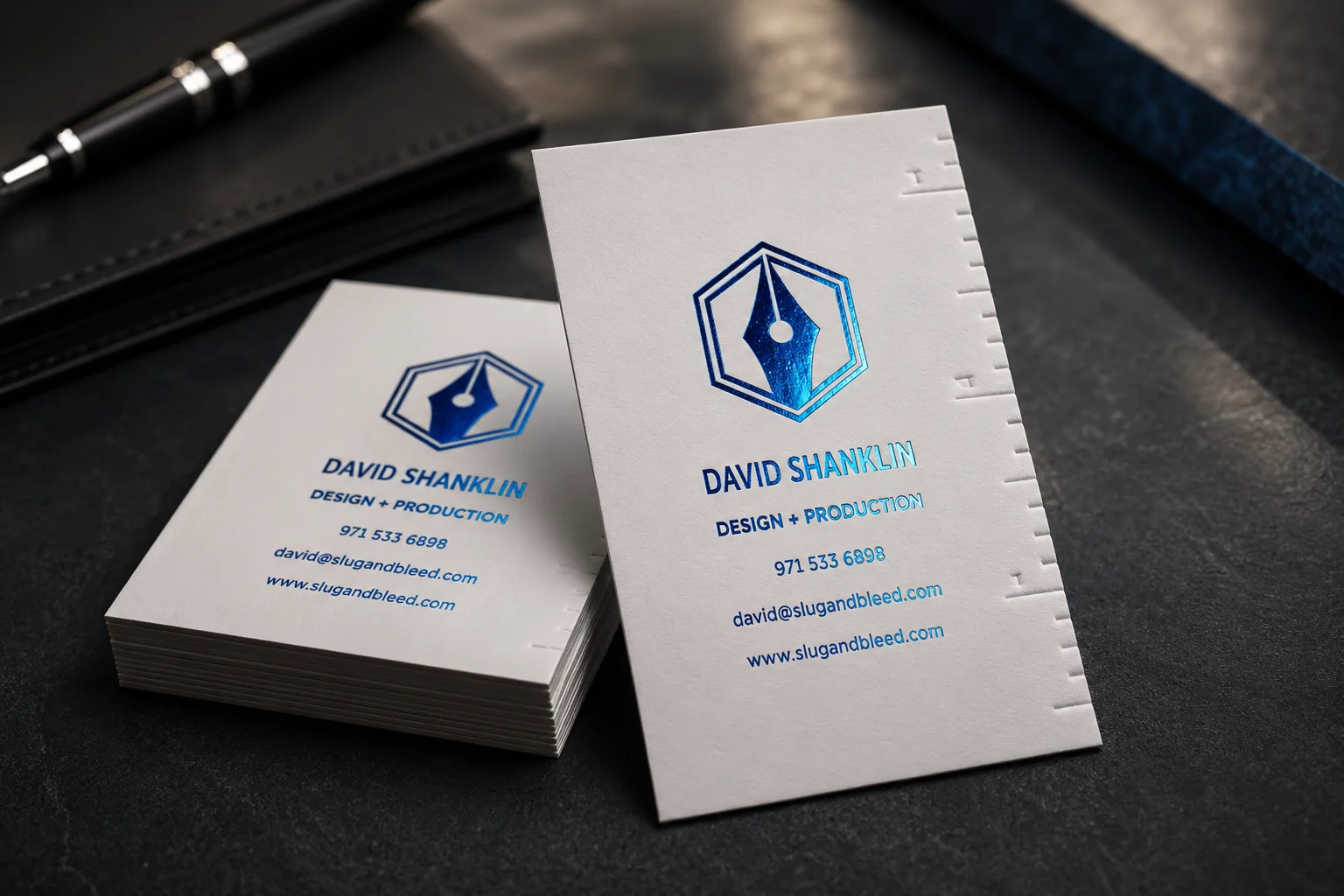 White business cards with blue-gold foil logo details and shallow debossed marks on a clean professional layout.