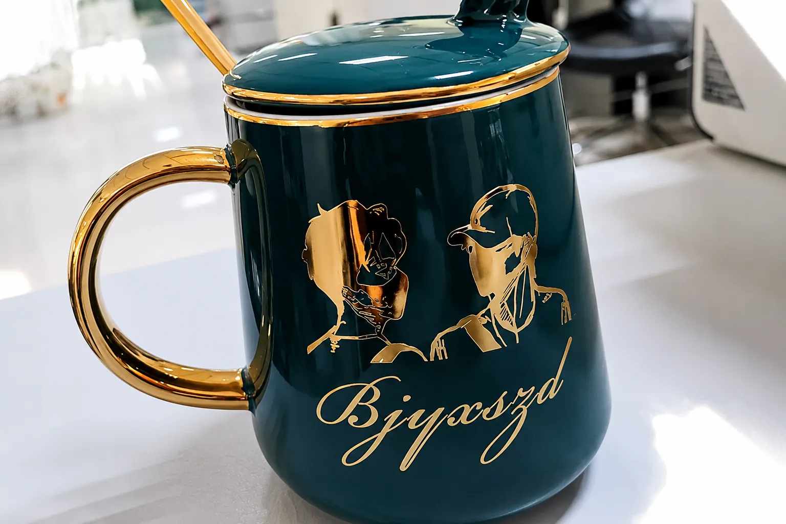 Gold metal transfer decal applied to a green ceramic mug