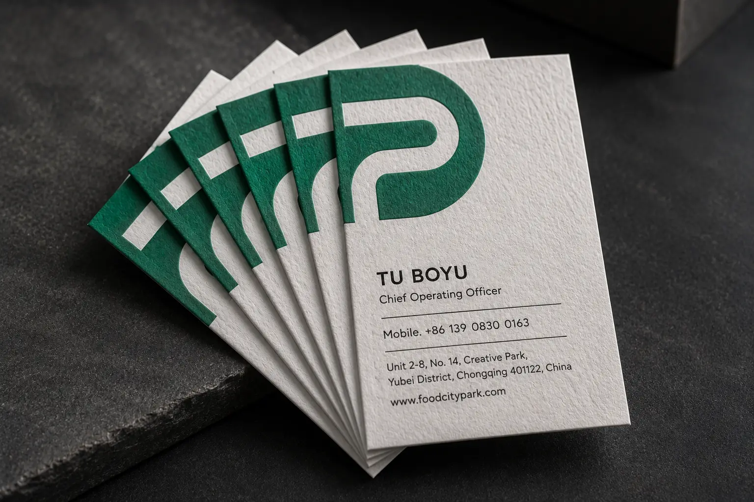 White cotton business card set with bold green printed logo and clean brand information layout.