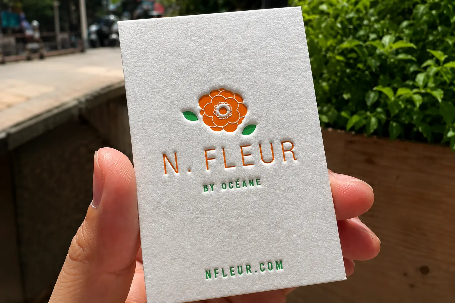 Handheld white cotton paper business card with orange floral logo