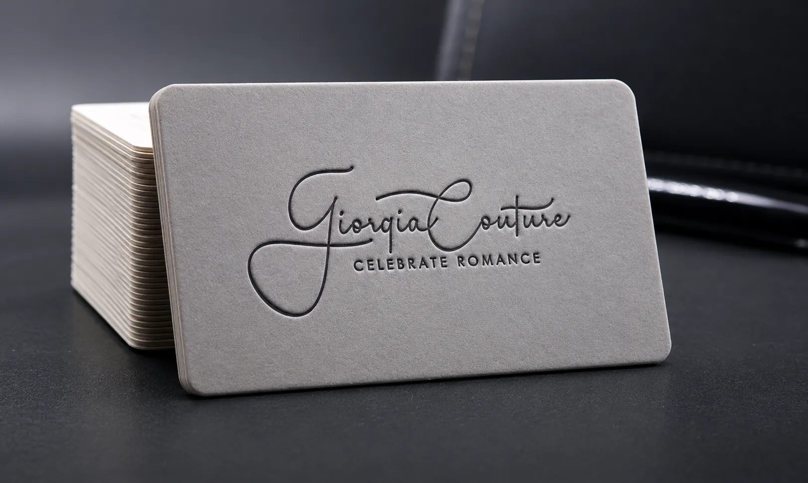 Minimal light business card stack with subtle blind deboss logo detail and clean script typography.