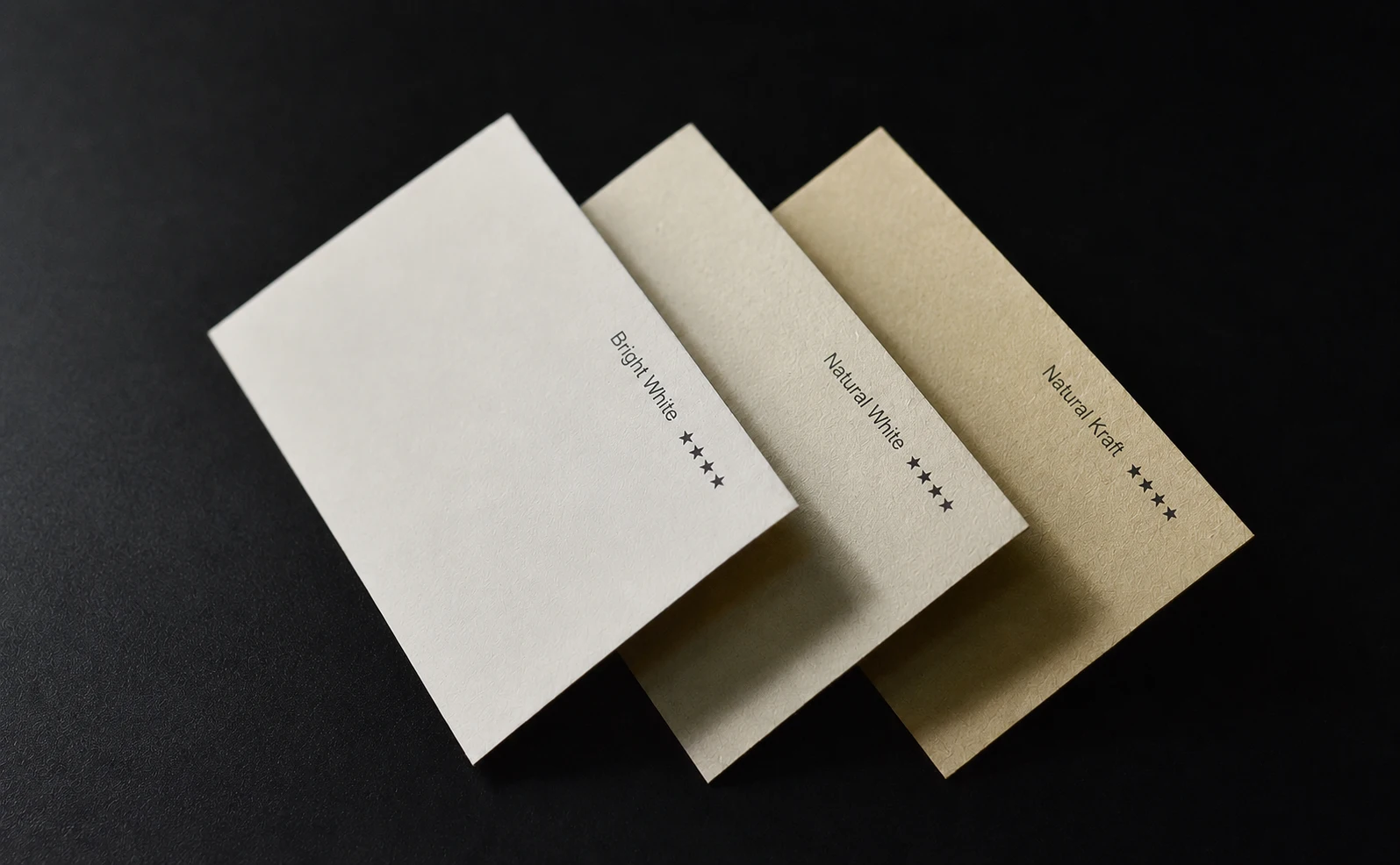 Natural white and ivory FSC-certified recycled paper business card set on a dark background