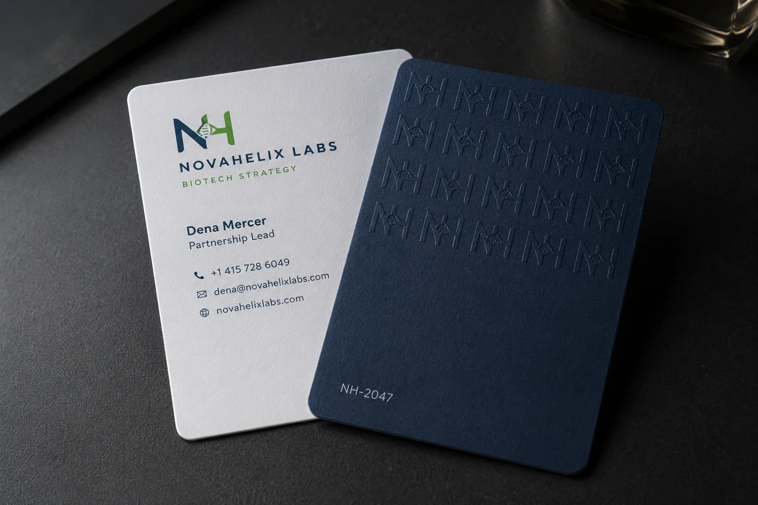 Navy business card with an all-over repeating blind deboss logo pattern paired with a clean white contact card.