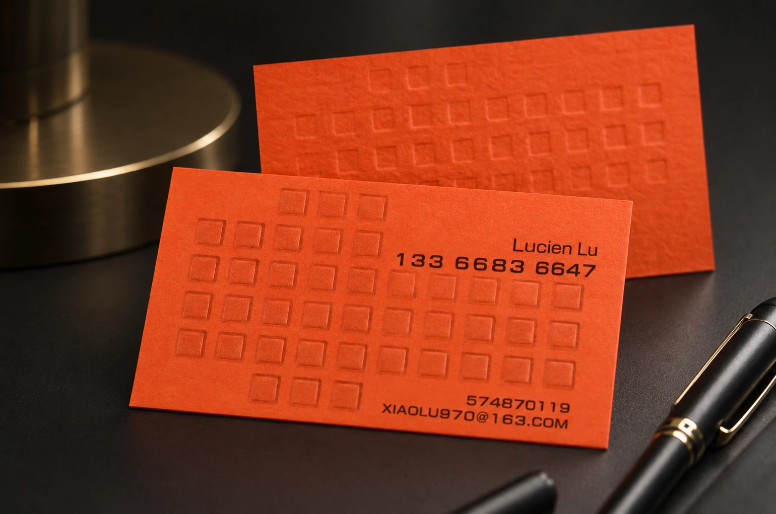 Orange FSC-certified recycled paper business cards with embossed texture and minimalist black printing