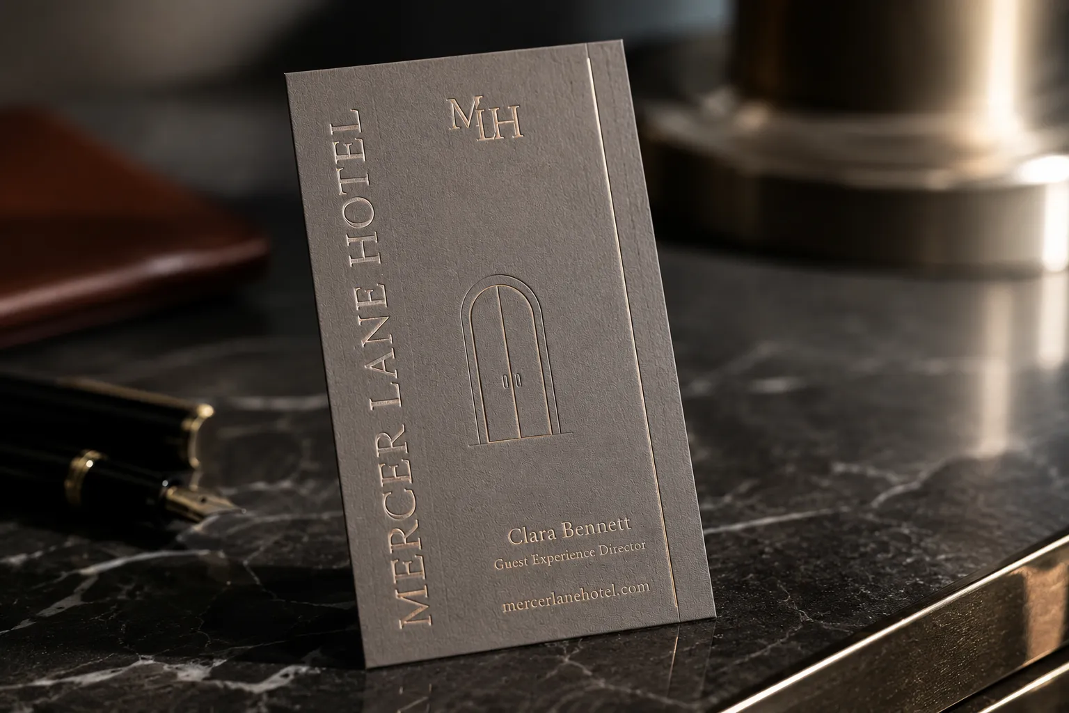 Gray premium business card with subtle platinum satin foil detail and restrained hotel branding.