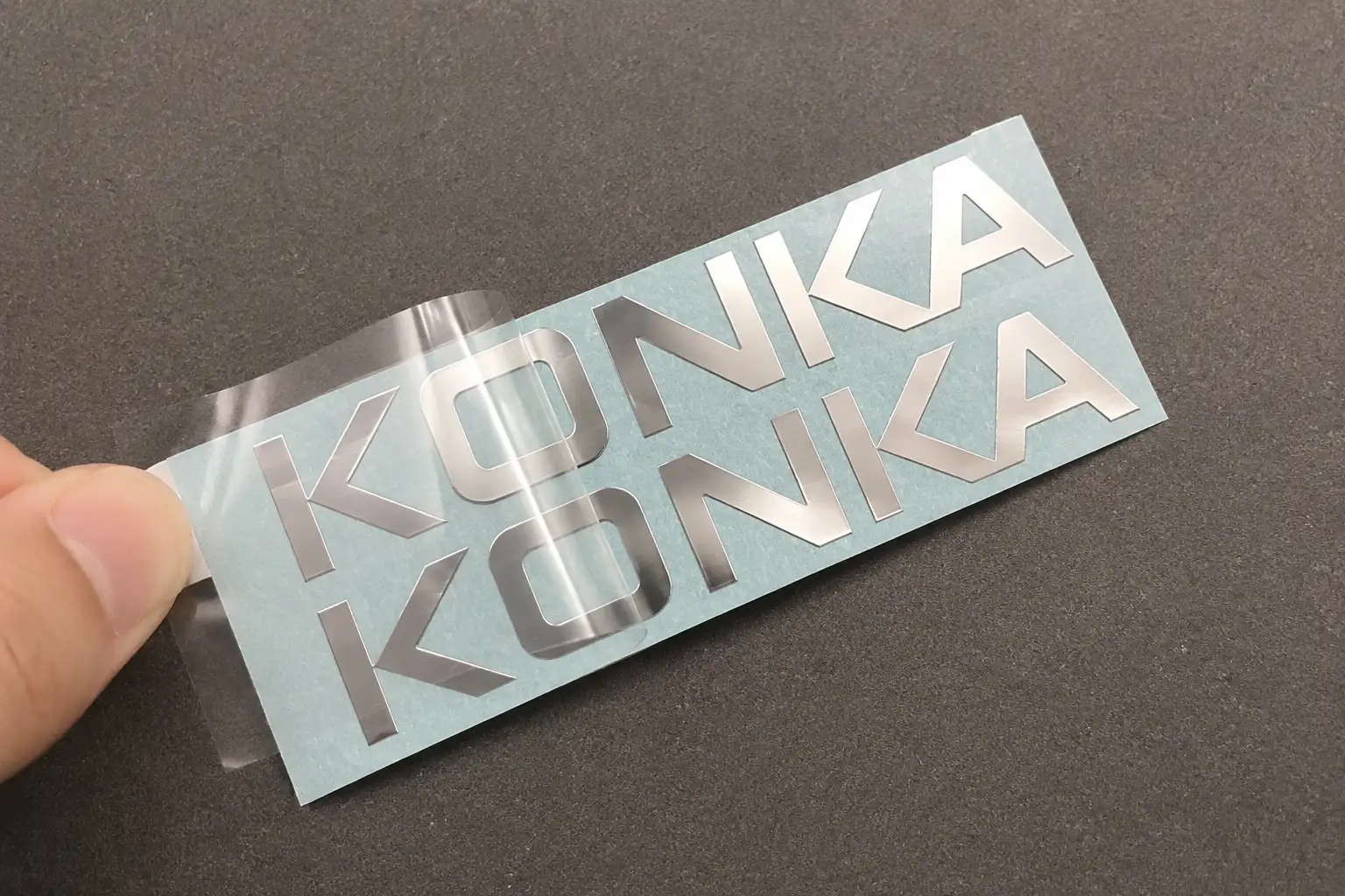 Thin silver metal transfer decal being applied with clear carrier film removed