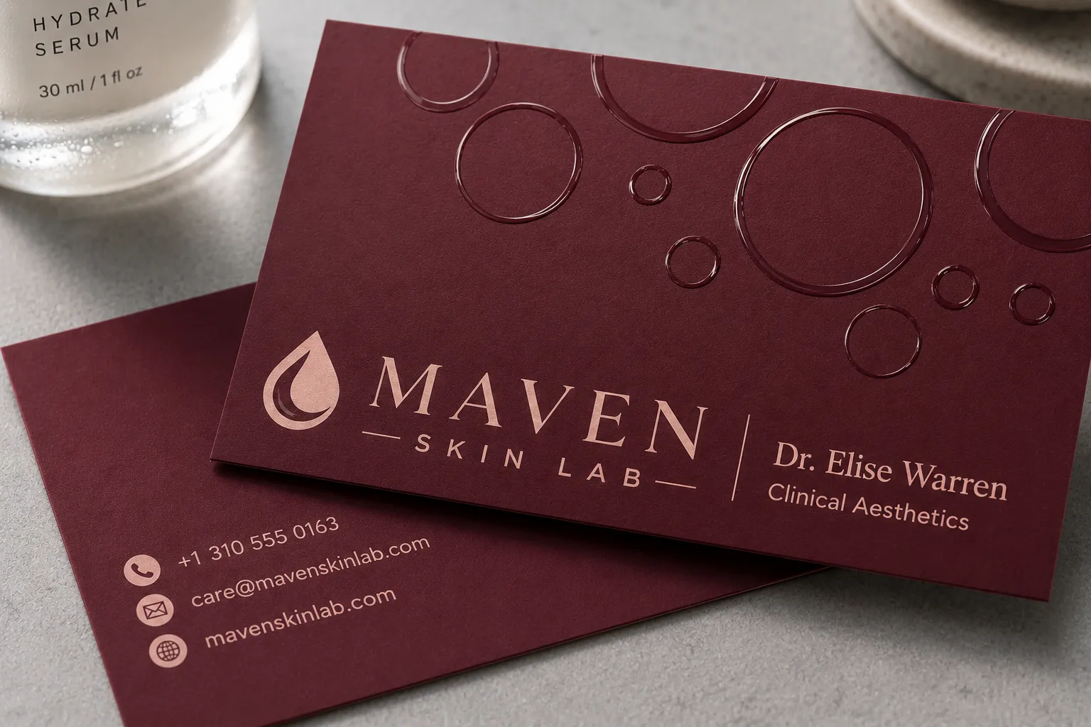 Burgundy soft touch business cards with glossy spot UV circles contrasting against a matte background.