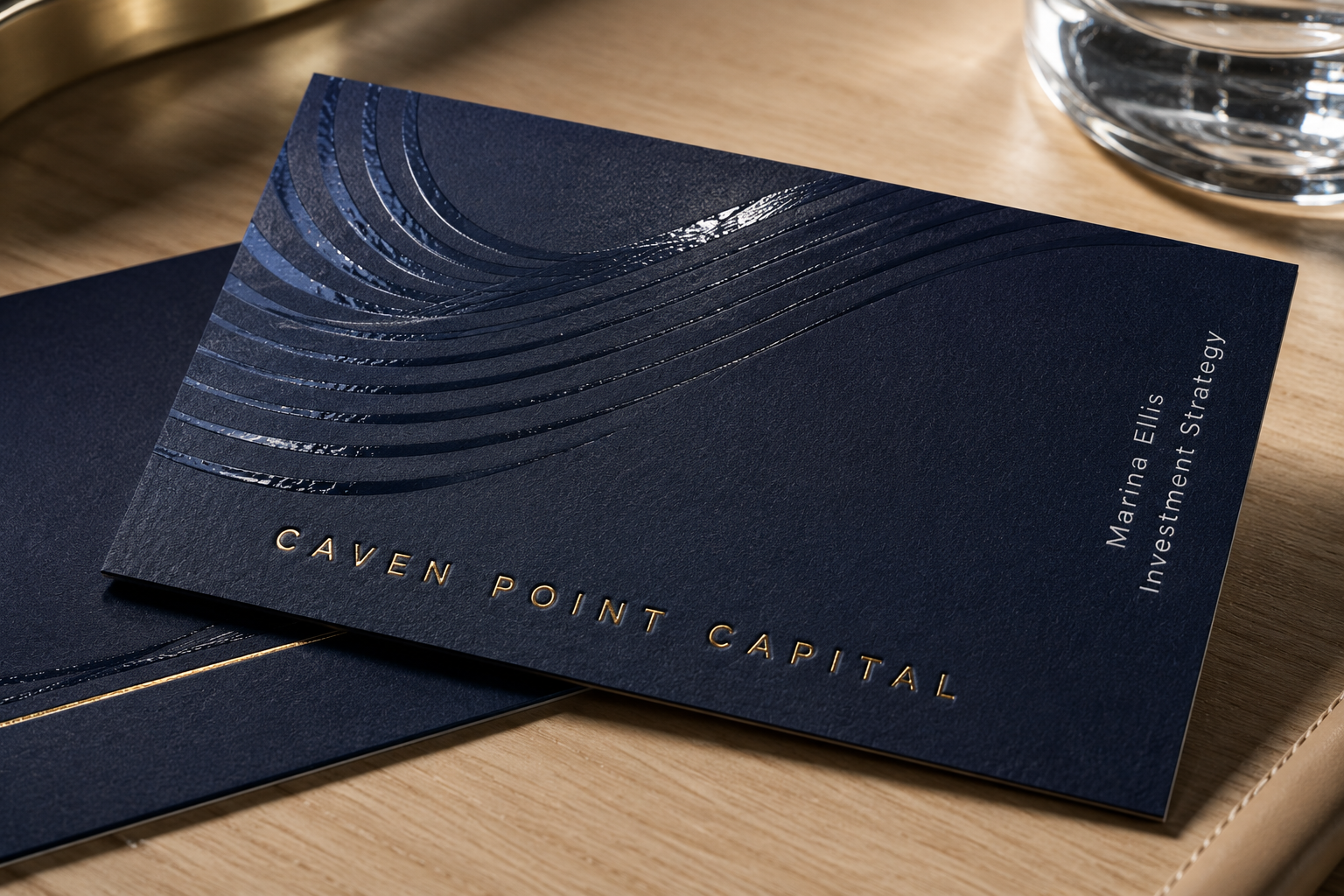 Dark navy business card with metallic foil lettering and glossy spot UV wave detail on a matte surface.