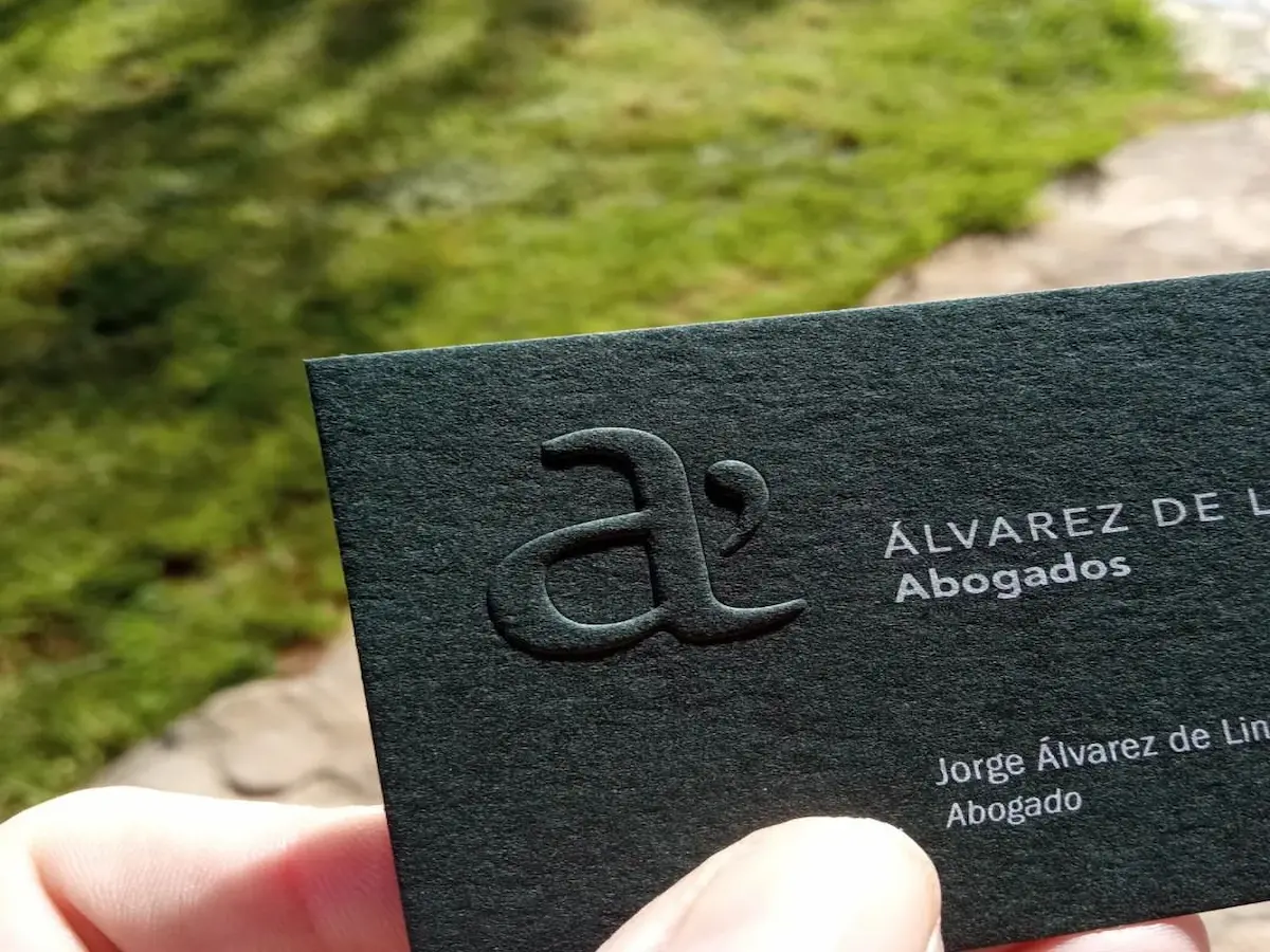 Close-up of a black cardstock business card with blind embossing and light-colored printed details.