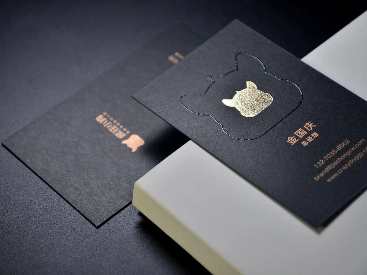 Black cardstock business cards with gold foil stamping and spot UV details.