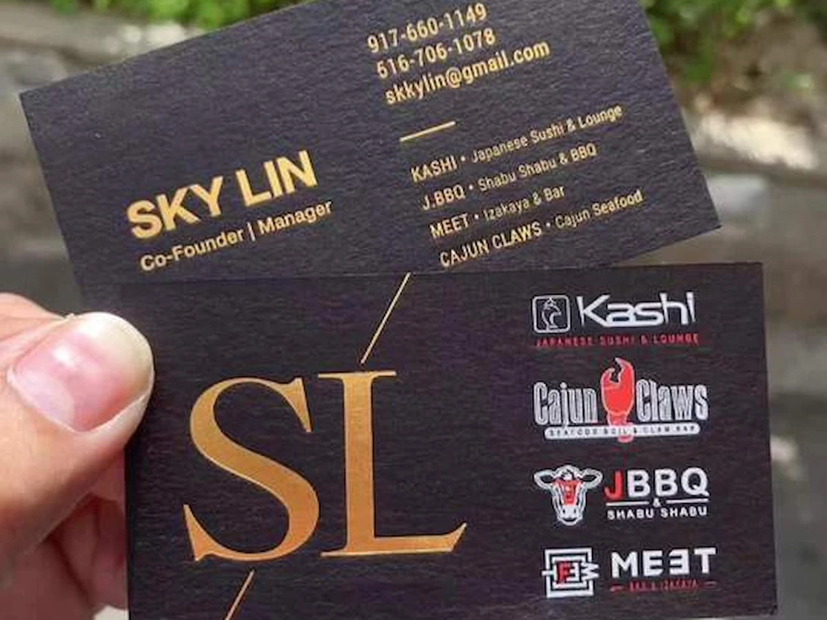 Two black cardstock business cards with gold, white and red design details.