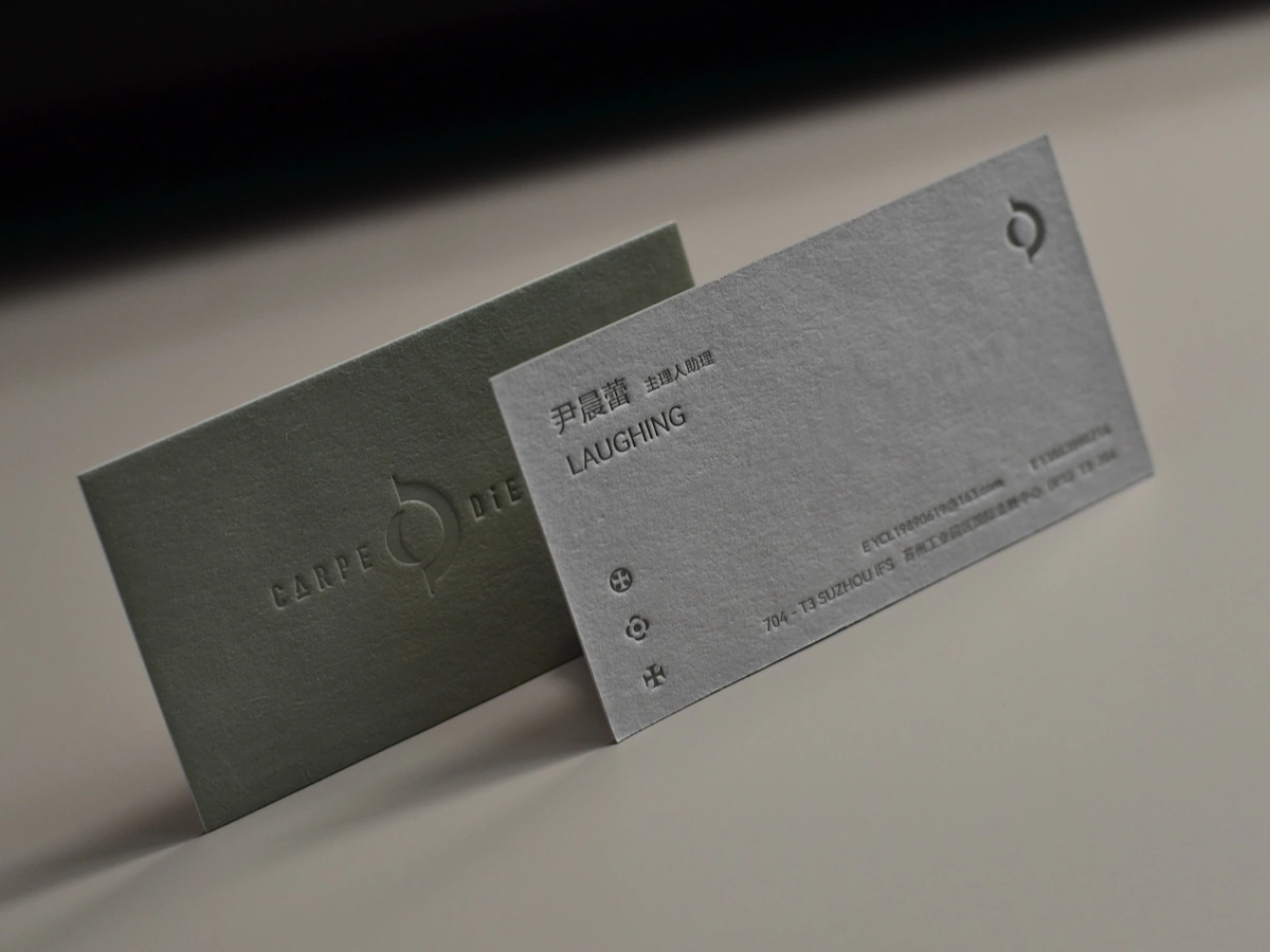 Two high-density cotton paper business cards with debossed lettering and printed details.