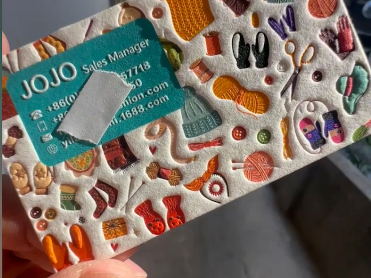 Low-density cotton paper print sample with colorful raised details beside a turquoise business card.