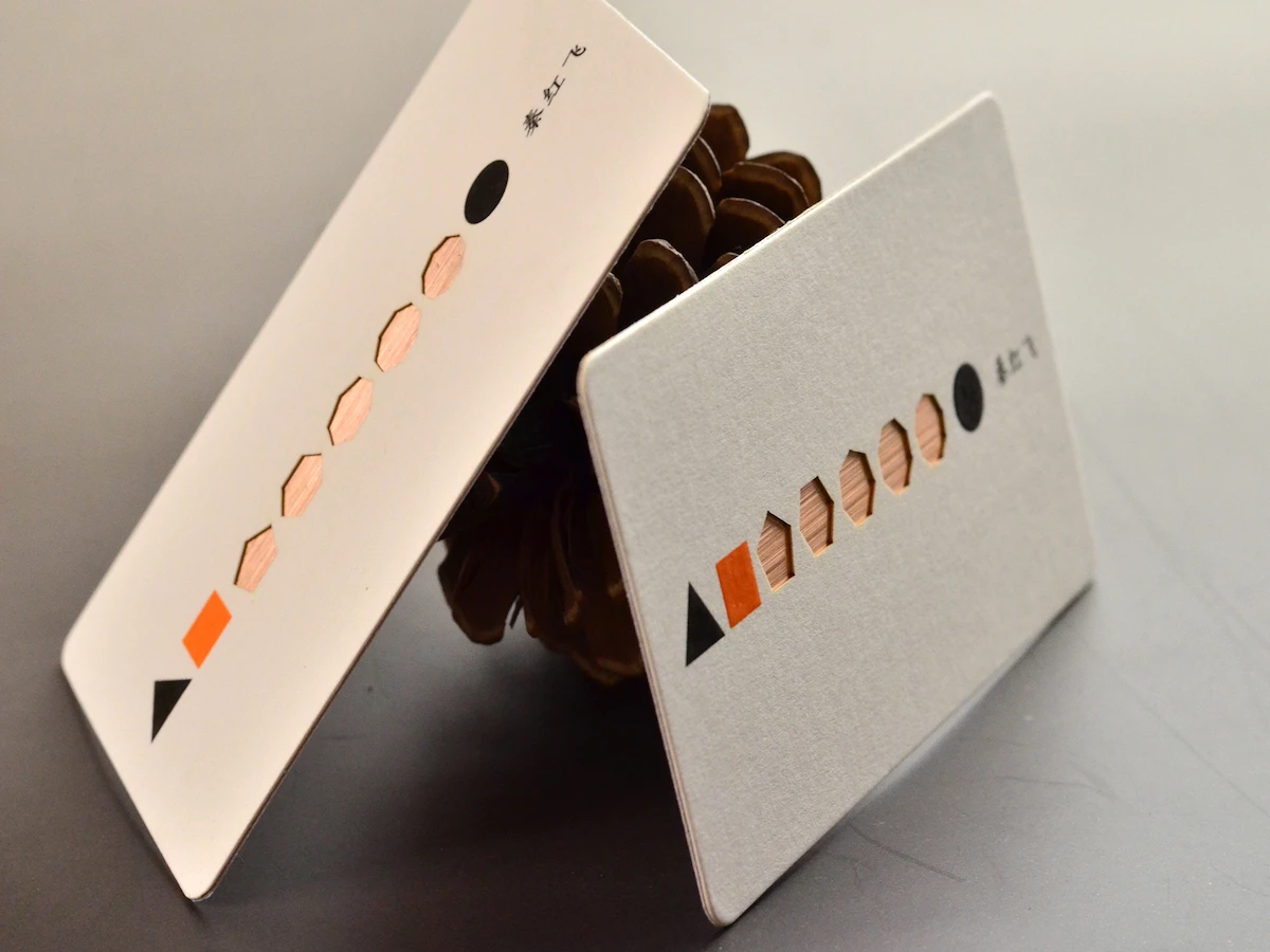 Two ivory business cards with a row of geometric openings and copper-toned details