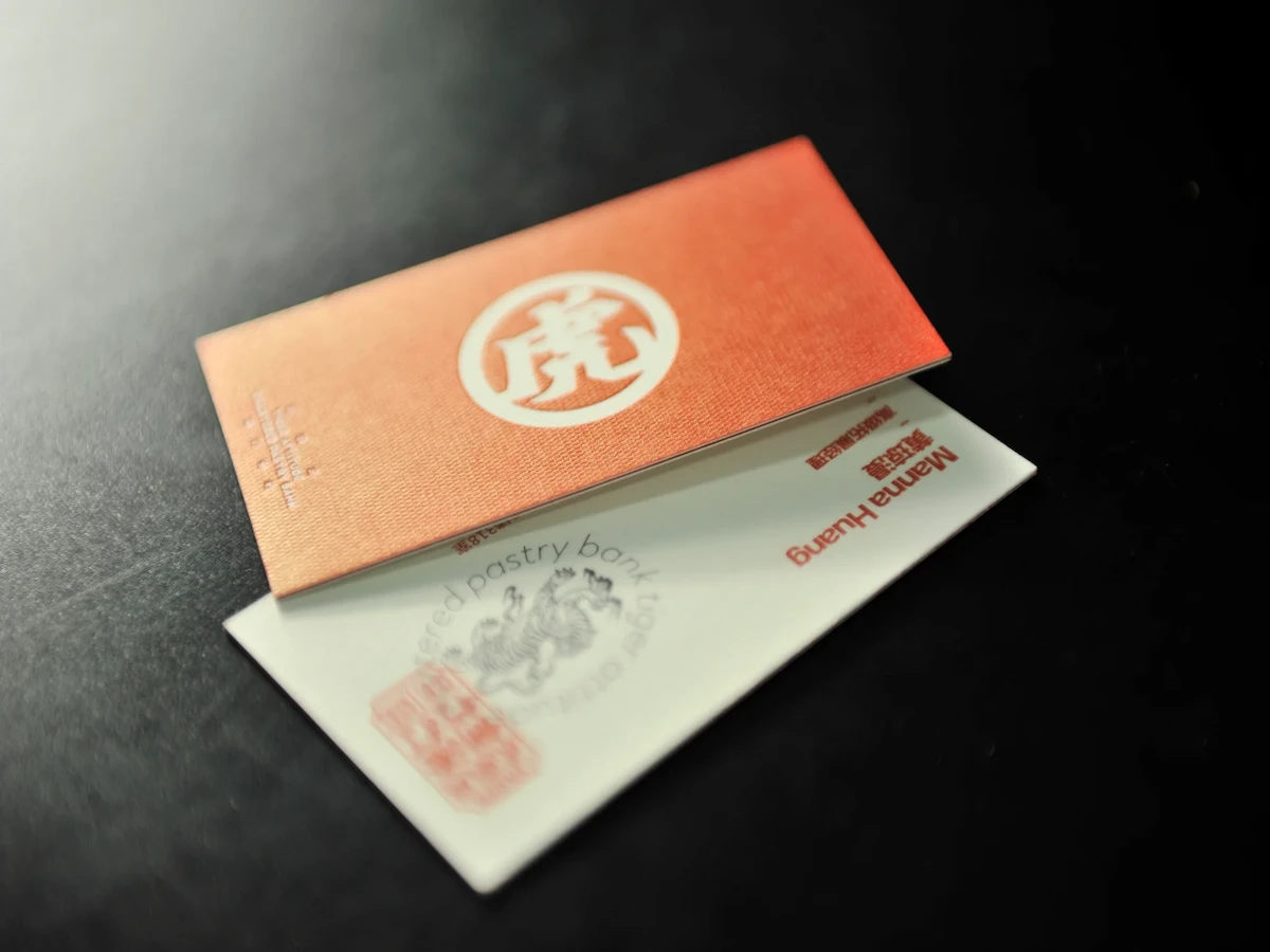 Copper-orange textured business card resting over a cream card with red printing