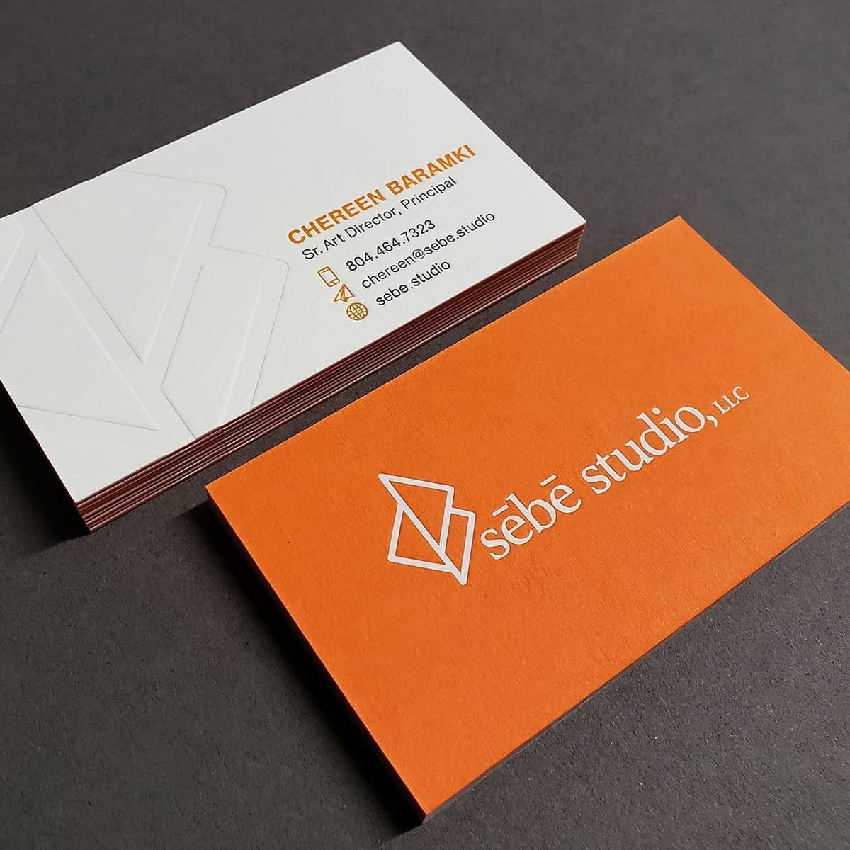 White and orange business card samples with printed branding and contact details.