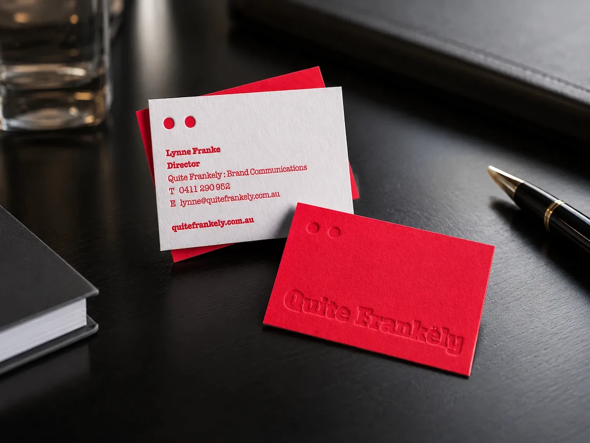 Red and white business cards with two small round holes and tone-on-tone lettering on the red card