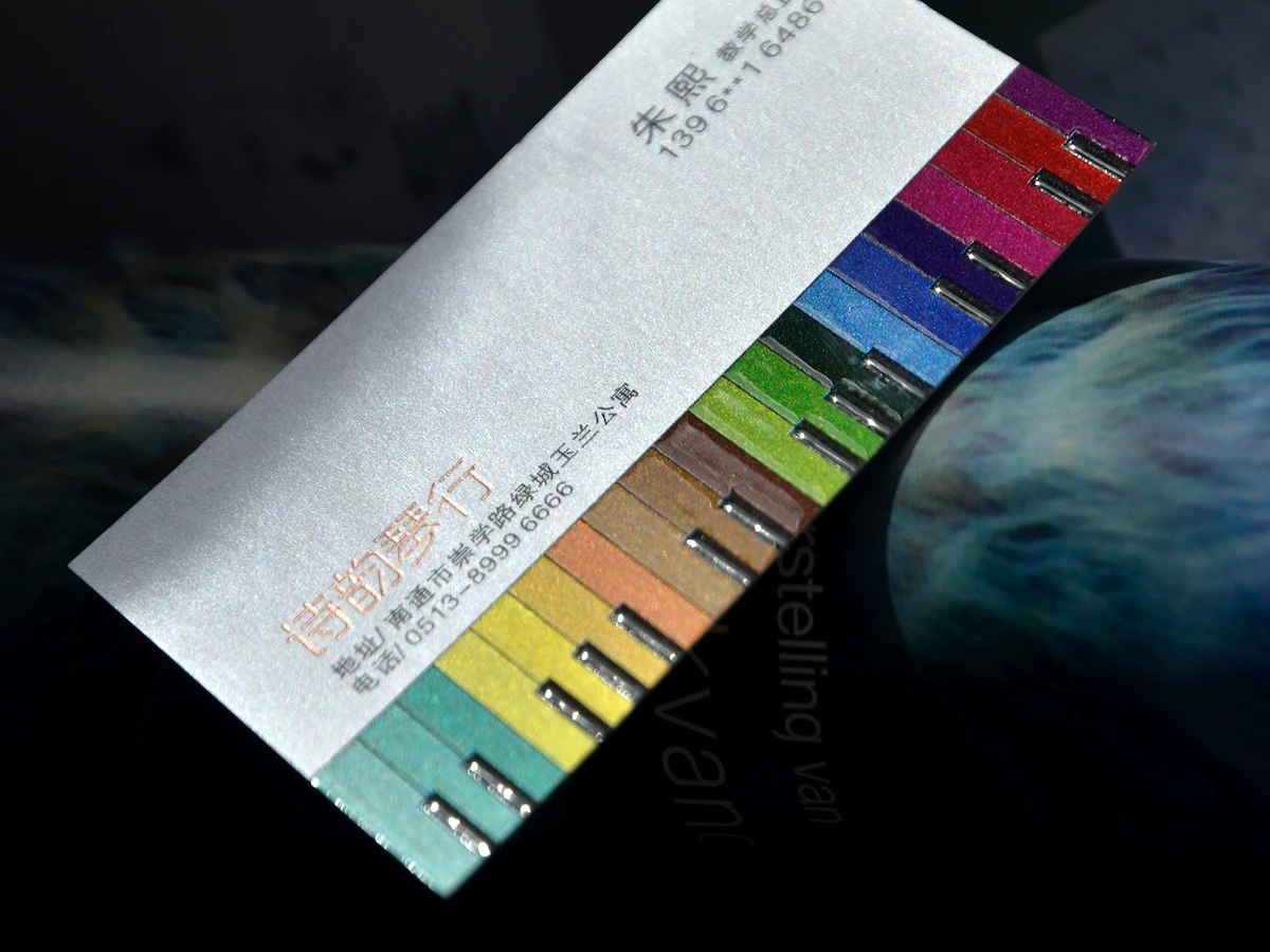 Silver business card resting over a fan of brightly colored paper samples