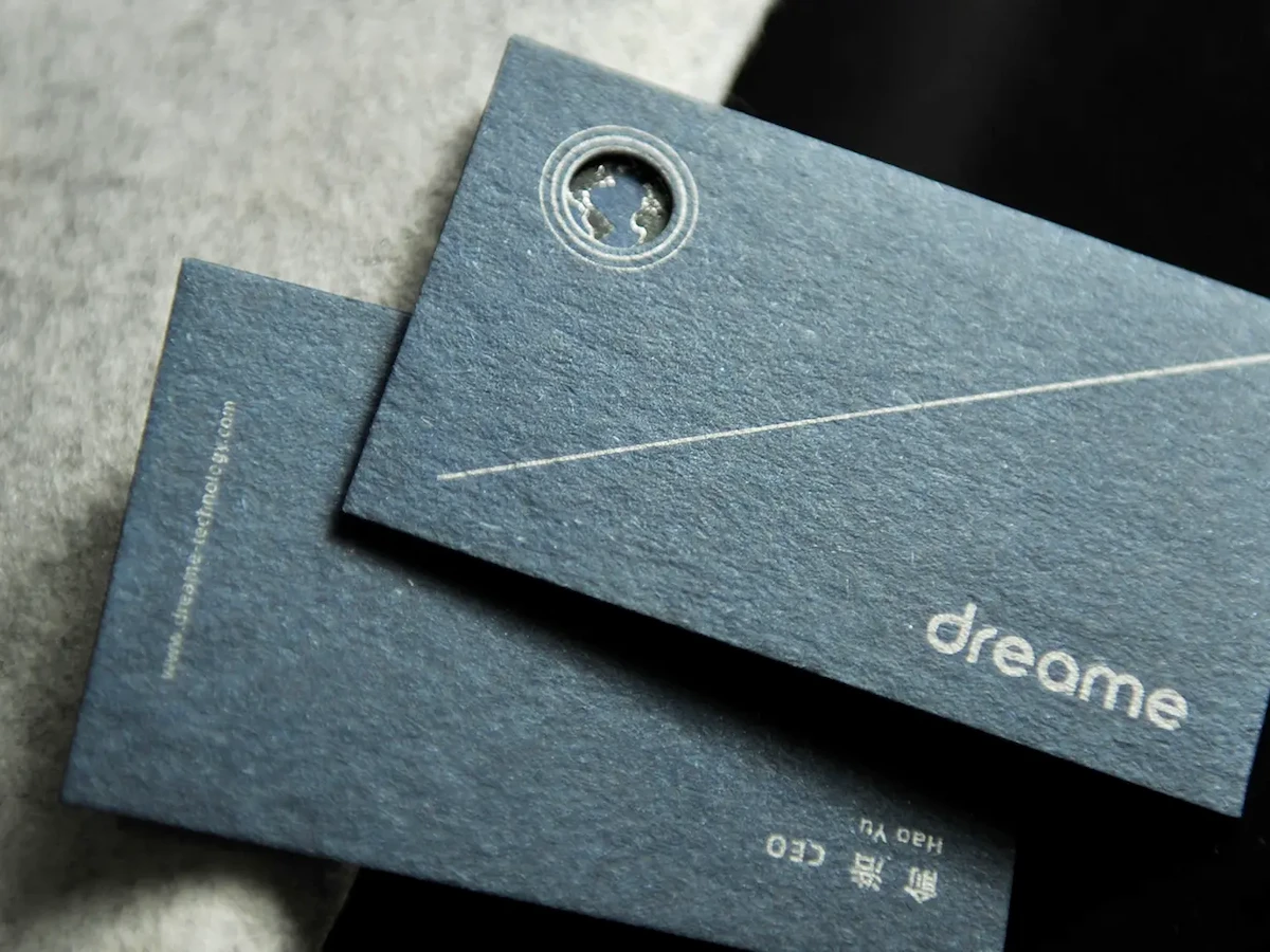 Two textured slate blue business cards, one with a small circular opening and fine white line details