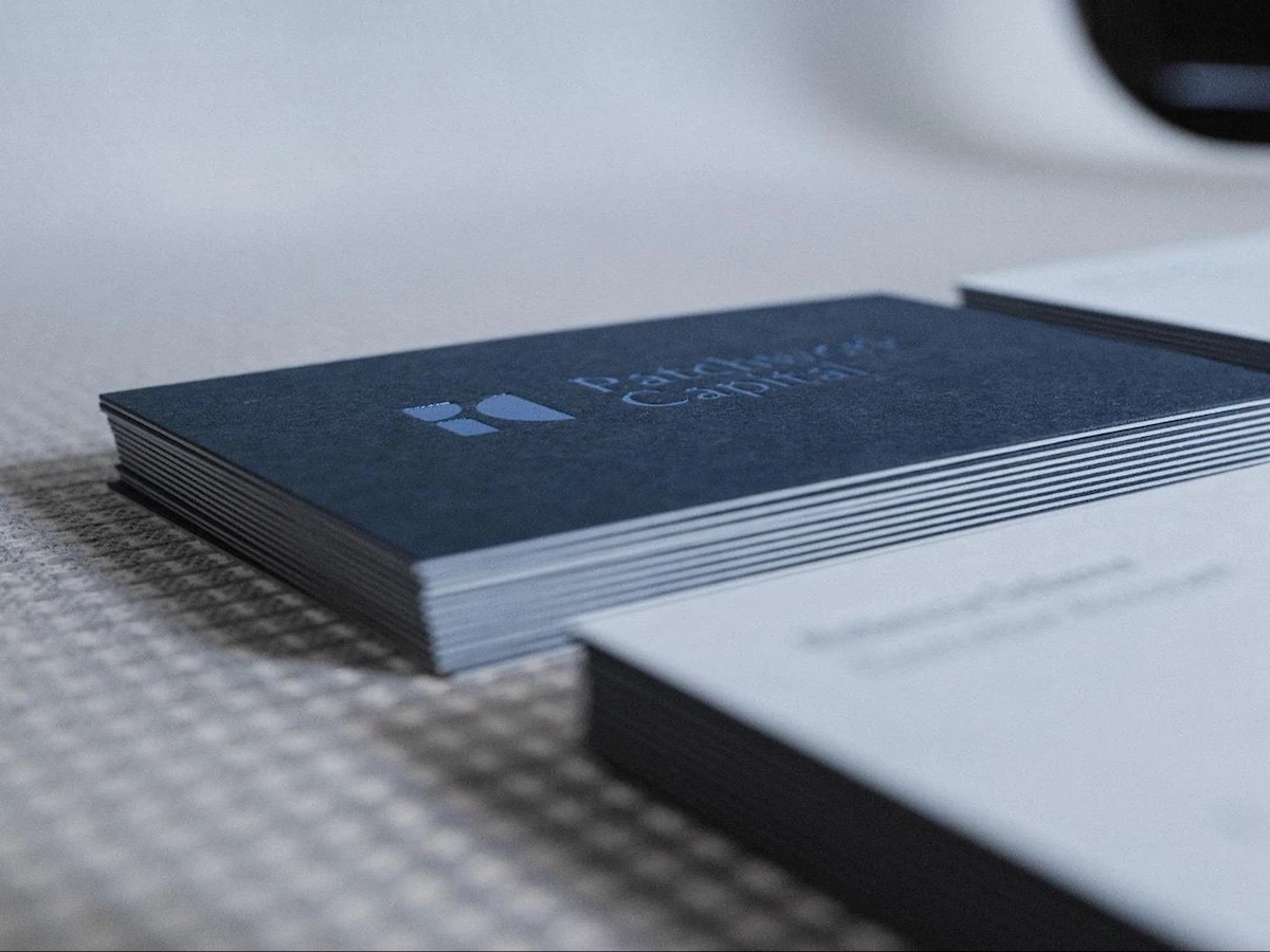 Stack of soft-touch paper business cards with visible white edges, one-sided full-bleed black printing, and silver foil stamping.