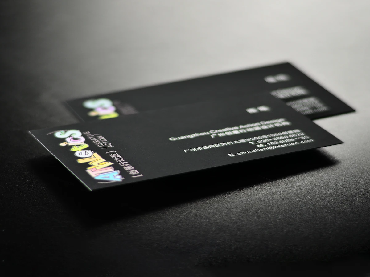 Soft-touch paper business cards with full-color printing on a black surface.